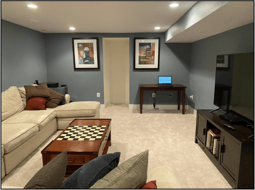 A snapshot of TPGi’s virtual escape room. A living area with a couch, TV, and desk.